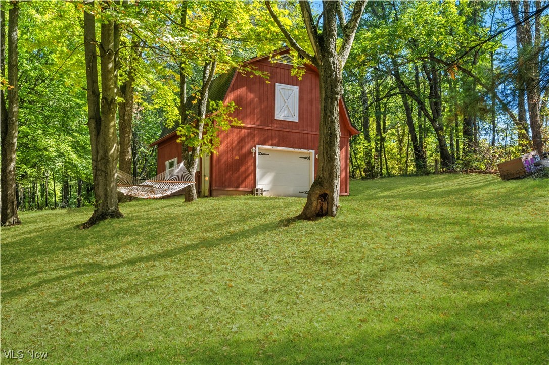 8193 Hartman Road Wadsworth, OH 44281 - Photo 38 of 50 View of green lawn featuring a detached garage, a barn, and a view of trees