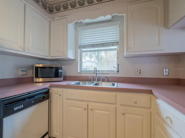 a kitchen with cabinets appliances a sink and a window