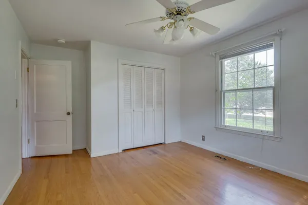 a view of an empty room with a window and wooden floor