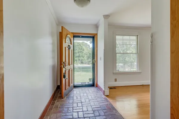 a view of a hallway with wooden floor and a bathroom