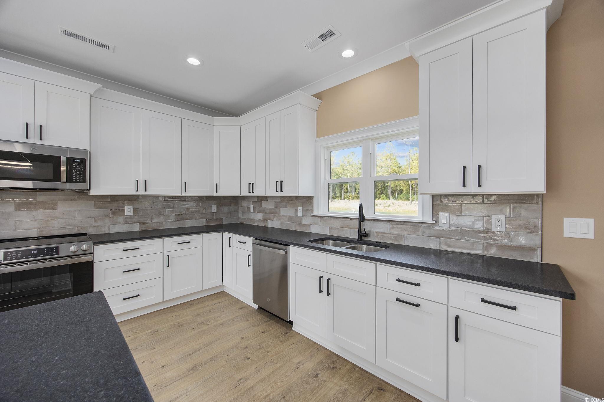 6914 Pauley Swamp Road Conway, SC 29527 - Photo 16 of 40 Kitchen featuring white cabinetry, light hardwood