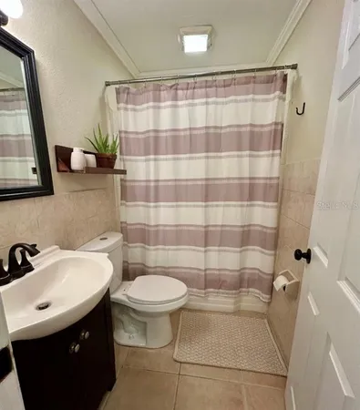 a bathroom with a sink a toilet a mirror a lamp and shower curtain