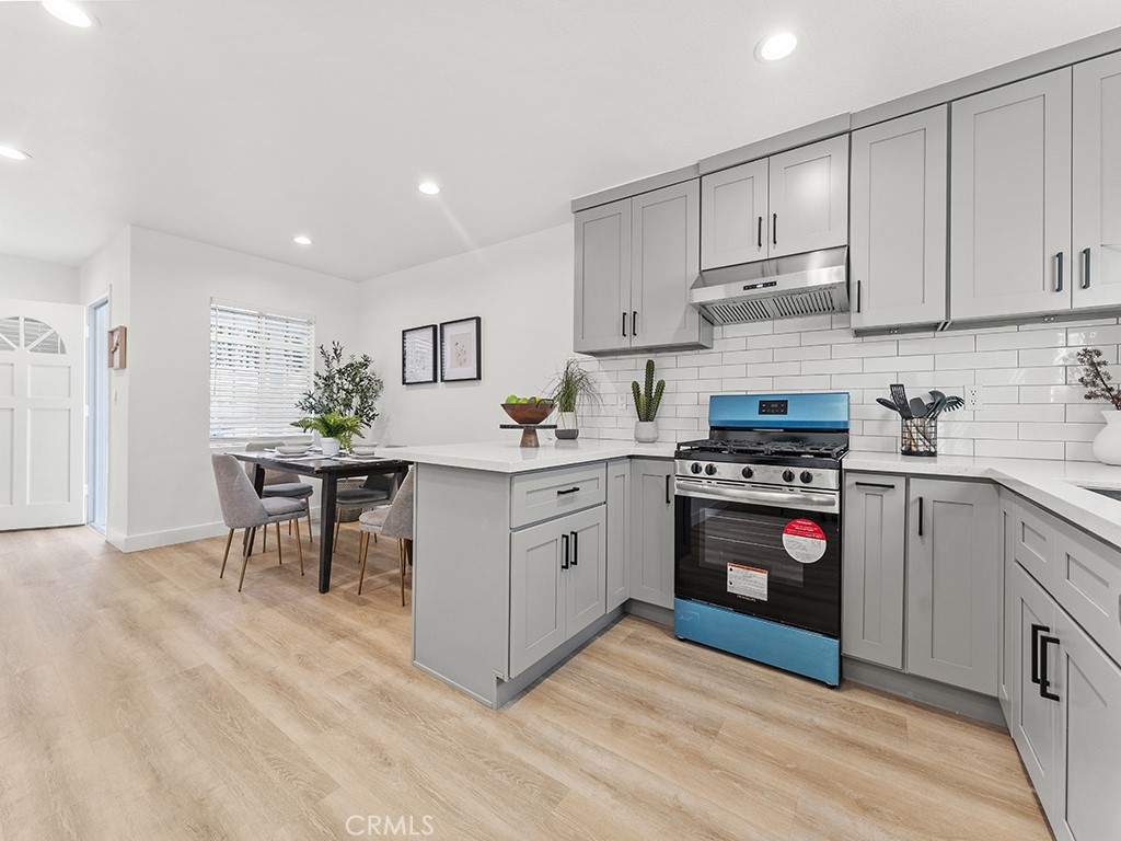 1056 Walter Avenue Tustin, CA 92780 - Photo 25 of 39 a kitchen with stainless steel appliances a stove a sink cabinets and a wooden floor