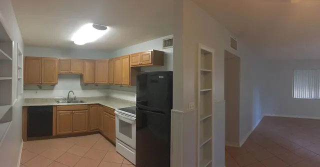 a kitchen with a sink a refrigerator and cabinets