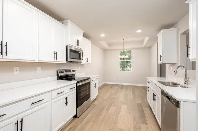 a kitchen with granite countertop a sink a stove a microwave a counter space and cabinets