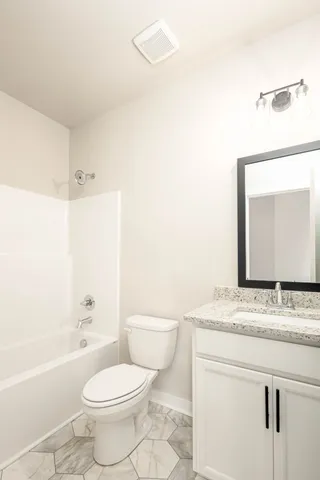 a bathroom with a granite countertop toilet sink and mirror