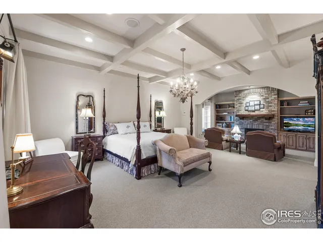 a spacious bedroom with bed a chandelier and a fireplace