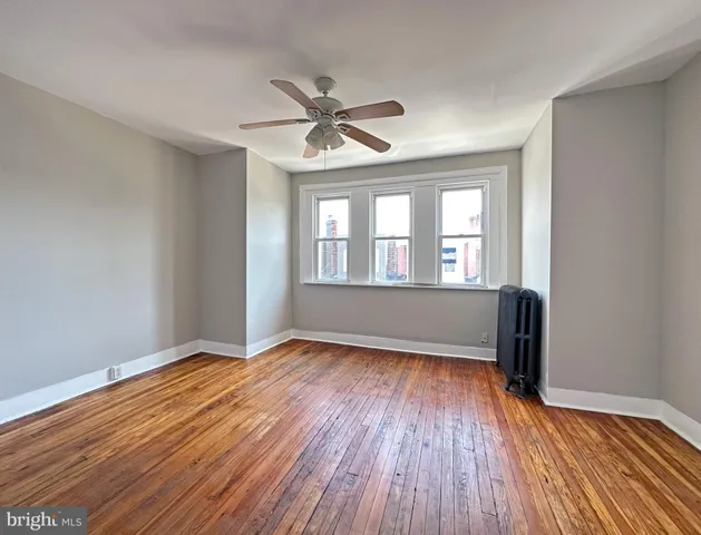 a view of empty room with wooden floor and fan