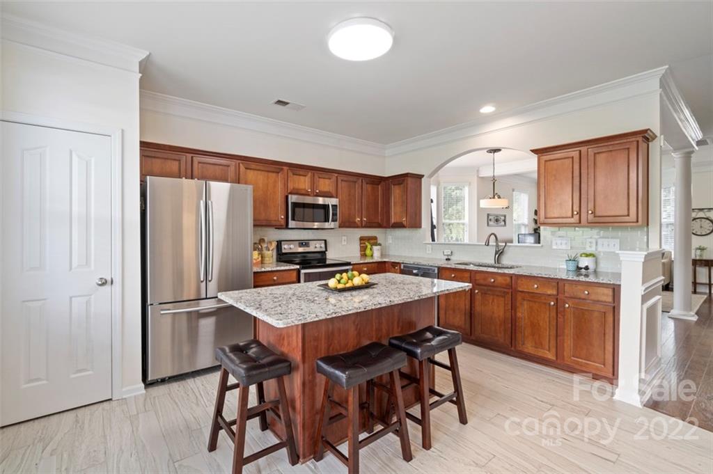 7383 Laurel Valley Road Charlotte, NC 28273 - Photo 4 of 37 a kitchen with stainless steel appliances granite countertop a refrigerator a stove a sink a table and chairs