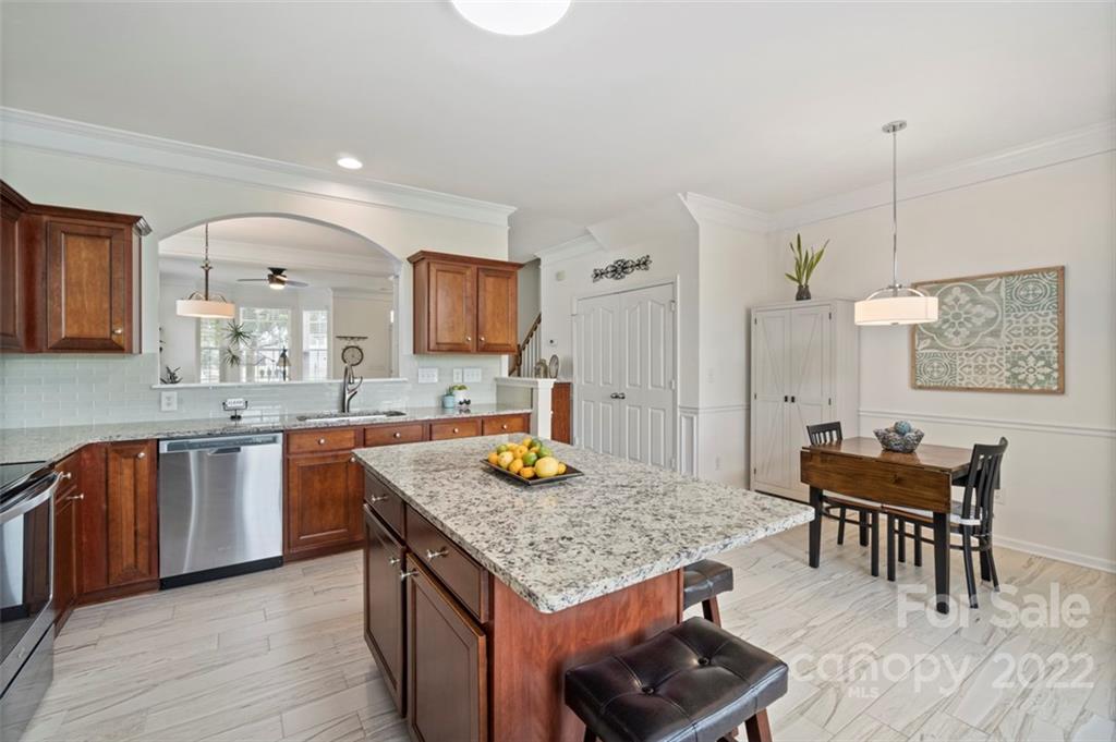 7383 Laurel Valley Road Charlotte, NC 28273 - Photo 7 of 37 a kitchen with stainless steel appliances granite countertop a stove a sink dishwasher a dining table and chairs with wooden floor