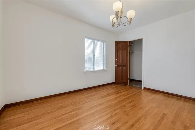 a view of empty room with wooden floor and chandelier