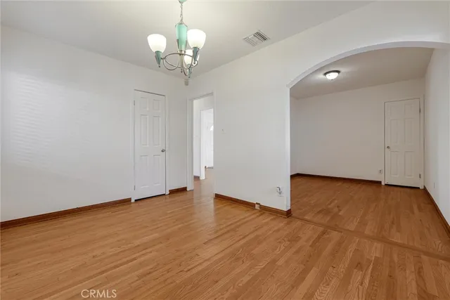 a view of empty room with wooden floor and chandelier