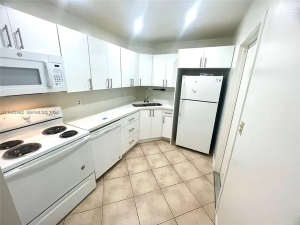 a kitchen with white cabinets a sink a stove a refrigerator and a window