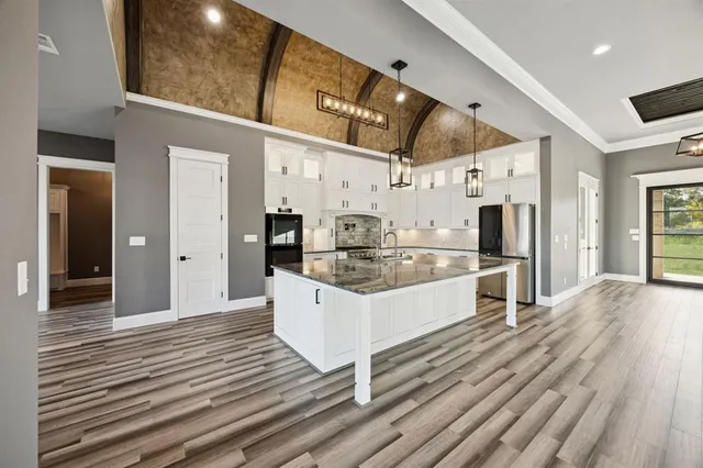 a large white kitchen with stainless steel appliances kitchen island granite countertop a large kitchen island a stove and a refrigerator