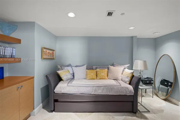 a bedroom with a bed a couch and a potted plant on the dresser