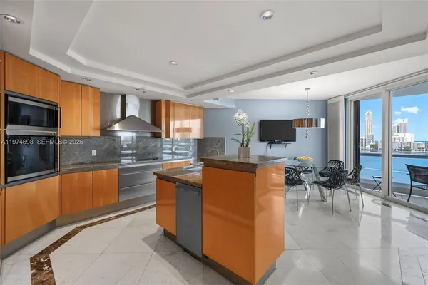 a kitchen with stainless steel appliances granite countertop a stove top oven a sink dishwasher a dining table and chairs with wooden floor