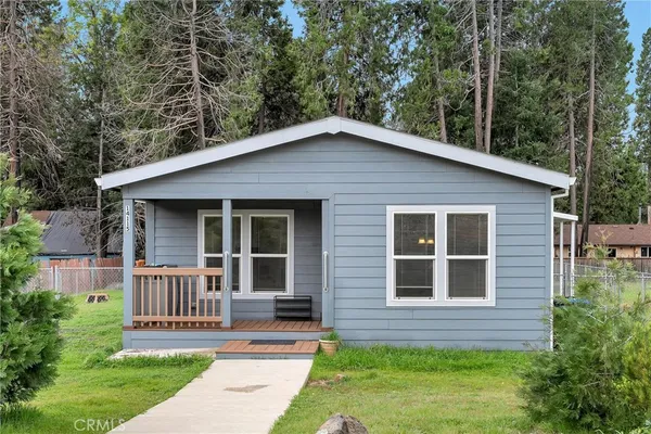 a brick house with a small yard plants and large trees