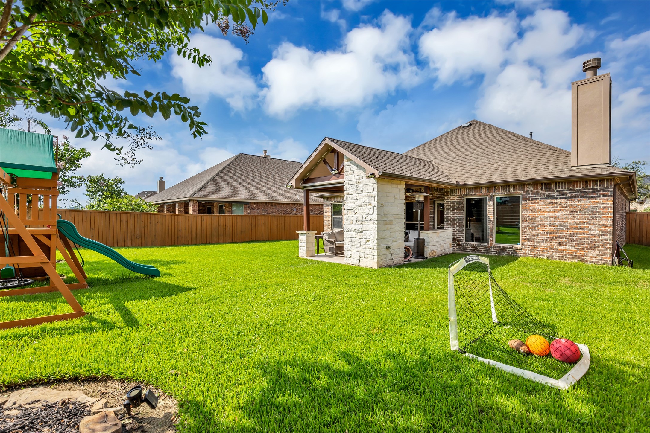 22907 Banff Brook Way Tomball, TX 77375 - Photo 21 of 26 Back view of the home showcasing a fully fenced backyard with plenty of open outdoor space, ideal for a variety of activities and future improvements.