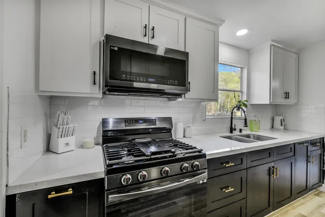 a kitchen with stainless steel appliances a sink a stove and microwave