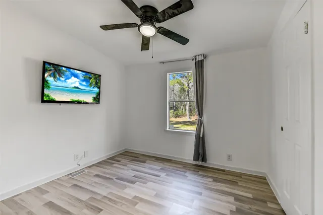 an empty room with windows and chandelier fan