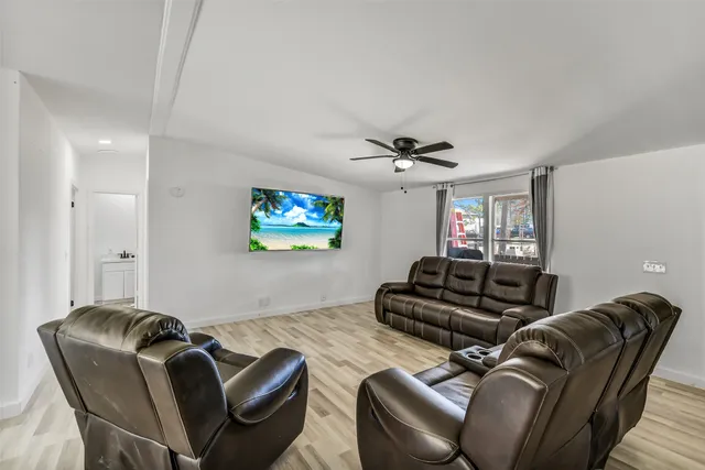 a living room with furniture ceiling fan and a flat screen tv
