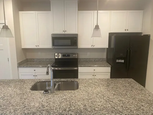 a kitchen with stainless steel appliances granite countertop a refrigerator and a stove