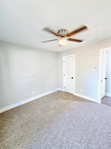 an empty room with wooden floor fireplace and windows