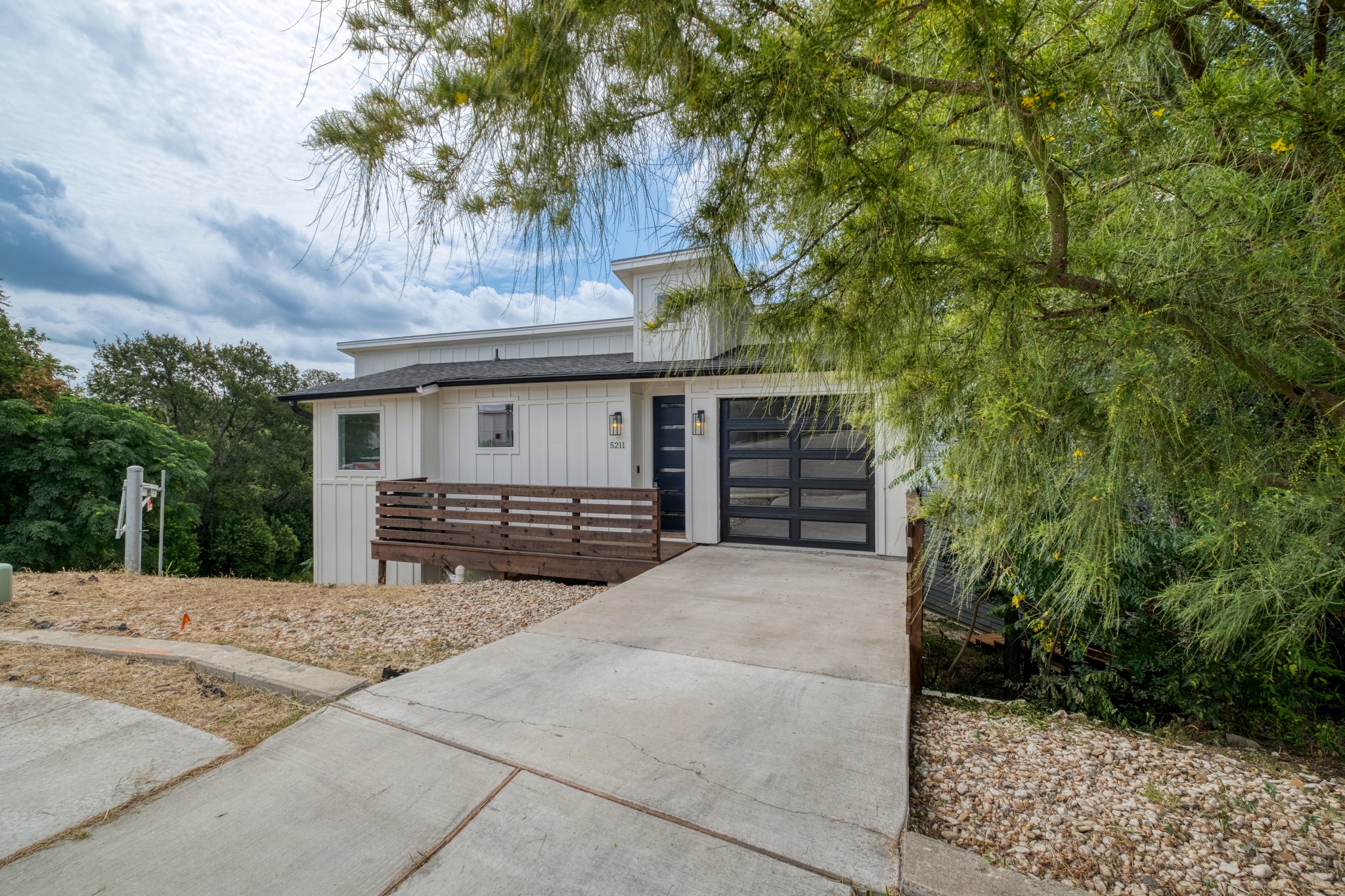5211 Rob-Scott Street Austin, TX 78721 - Photo 22 of 24 A modern facade with a sleek garage door and inviting front porch complements the natural, sloping landscape.