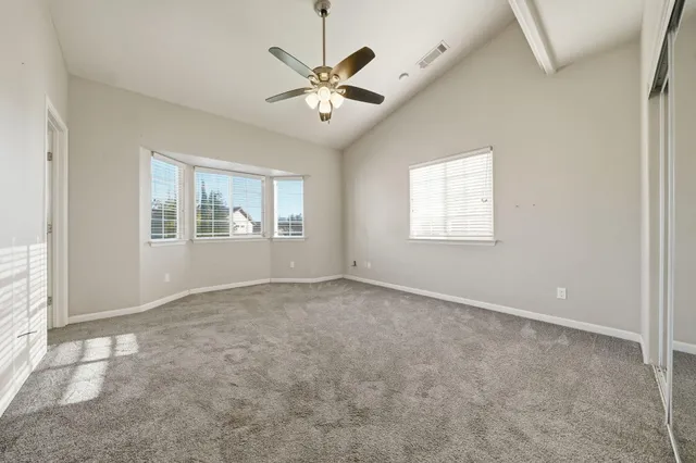 an empty room with windows and fan