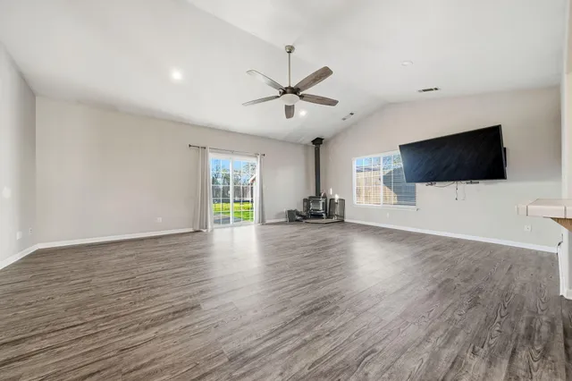 a view of a livingroom with a flat screen tv ceiling fan and wooden floor