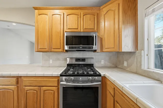a kitchen with granite countertop a stove top oven microwave and cabinets