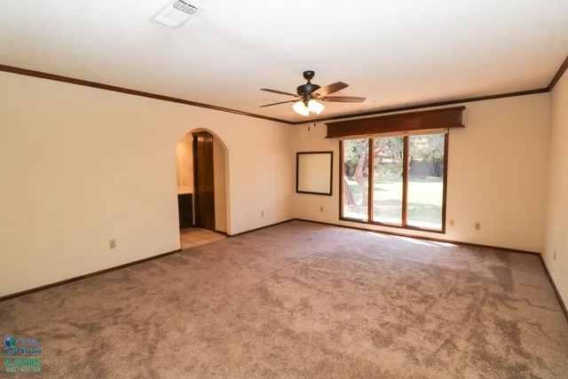 an empty room with windows and ceiling fan