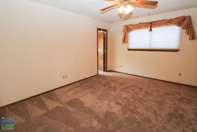 an empty room with a window and a chandelier fan