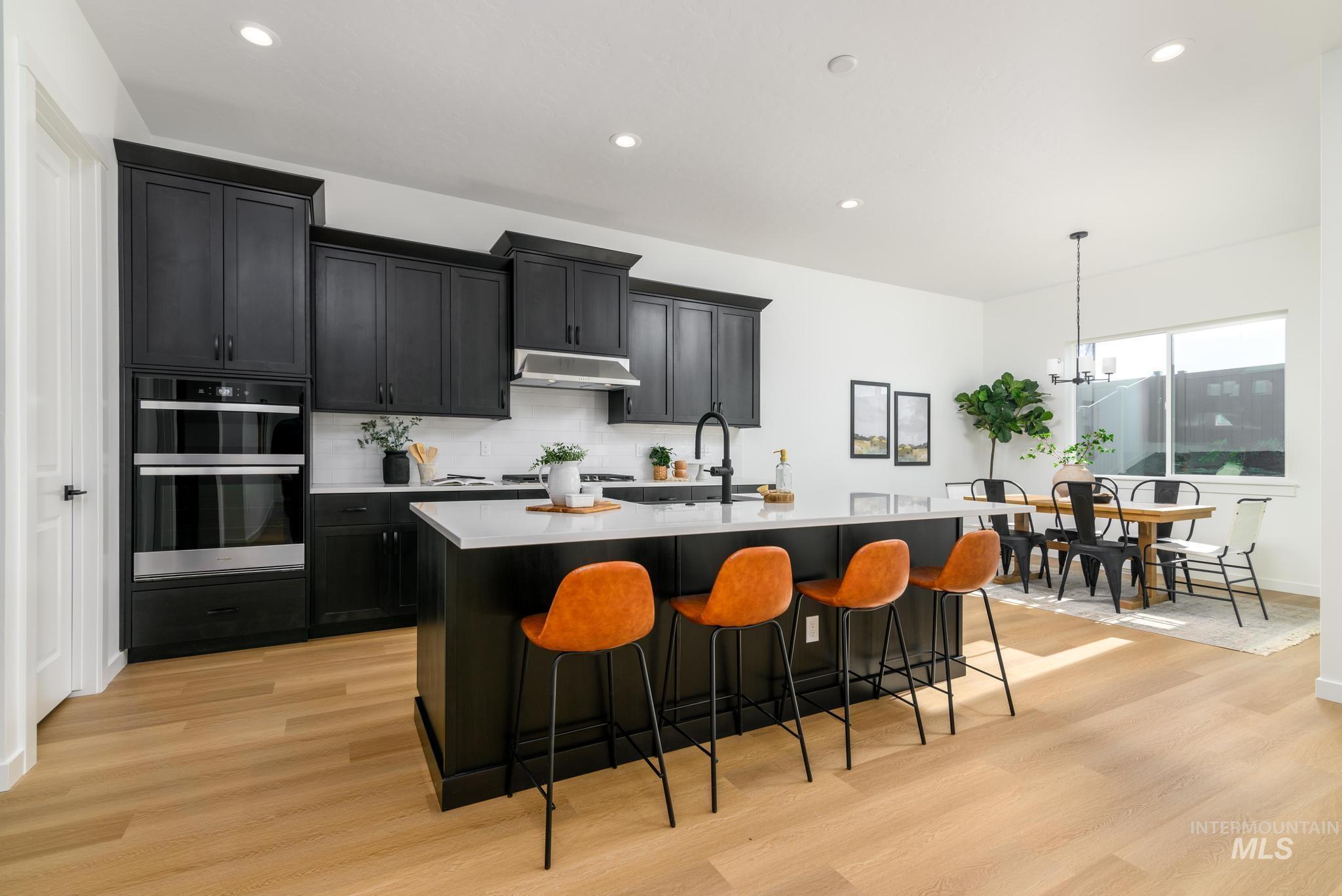 313 Crafts Street Caldwell, ID 83607 - Photo 4 of 9 Kitchen with dark cabinets, a breakfast bar, an island with sink, and light wood-style floors