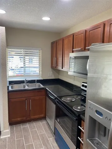 a kitchen with stainless steel appliances granite countertop a sink a stove and a refrigerator