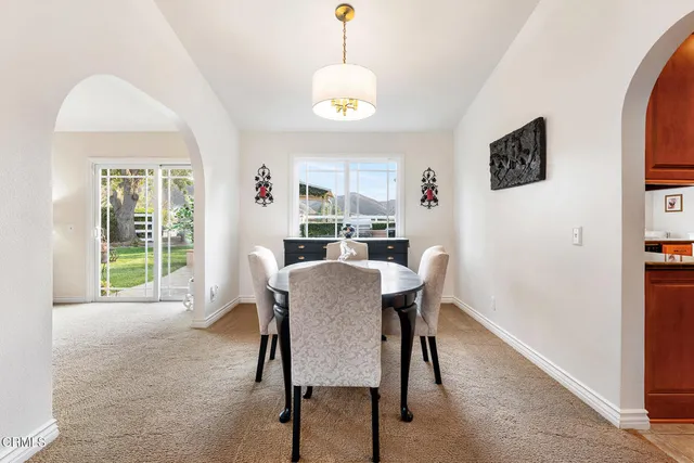 a view of a dining room with furniture a chandelier and a window