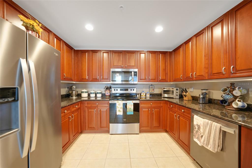 17094 Acapulco Road, Unit 313 Punta Gorda, FL 33955 - Photo 9 of 49 a kitchen with stainless steel appliances granite countertop a refrigerator a sink dishwasher a stove and a microwave oven with cabinets