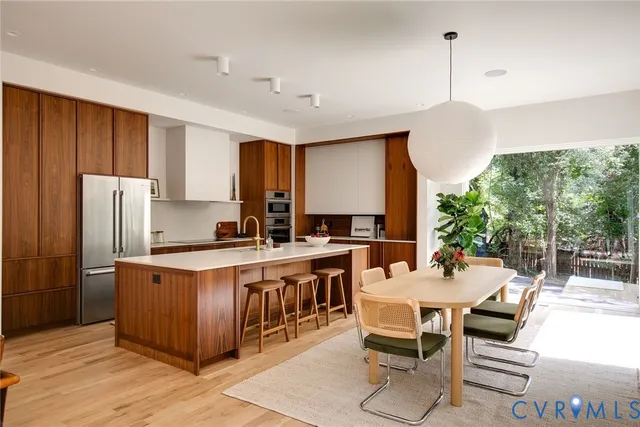 a kitchen with stainless steel appliances kitchen island granite countertop a table chairs and a refrigerator