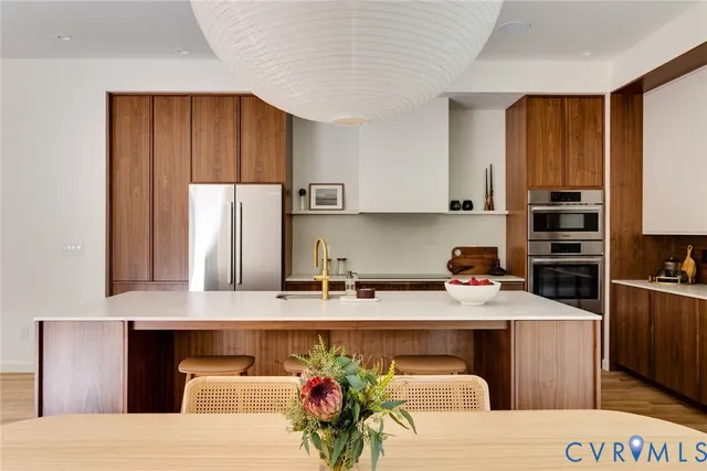 a kitchen with stainless steel appliances kitchen island granite countertop a refrigerator a stove a sink dishwasher and wooden cabinets with wooden floor