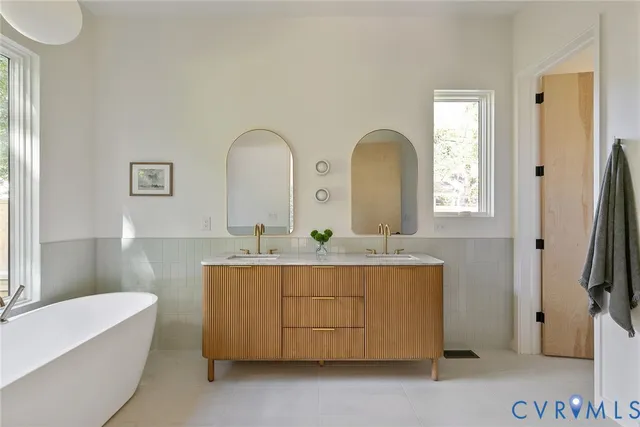 a bathroom with a double vanity sink a mirror and a bathtub