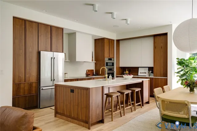 a kitchen with a refrigerator a sink dishwasher and wooden cabinets