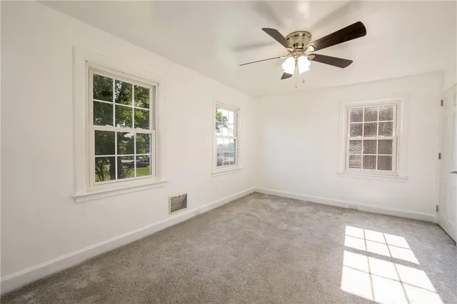 an empty room with windows and fan