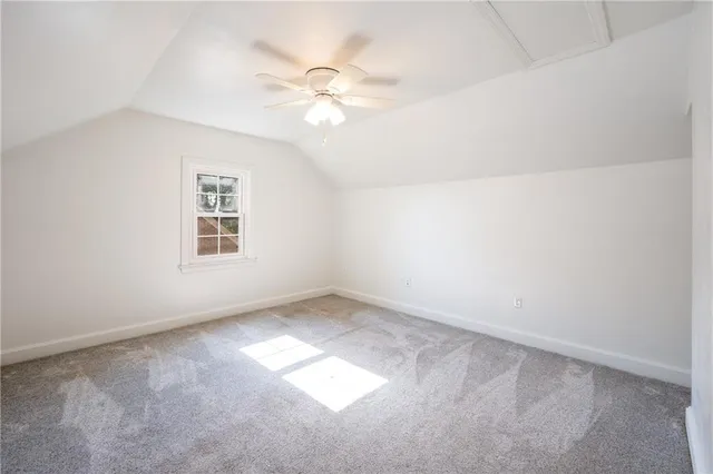 an empty room with windows and chandelier fan