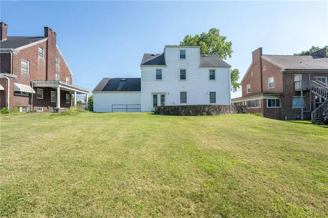 a view of a house with a big yard and large trees