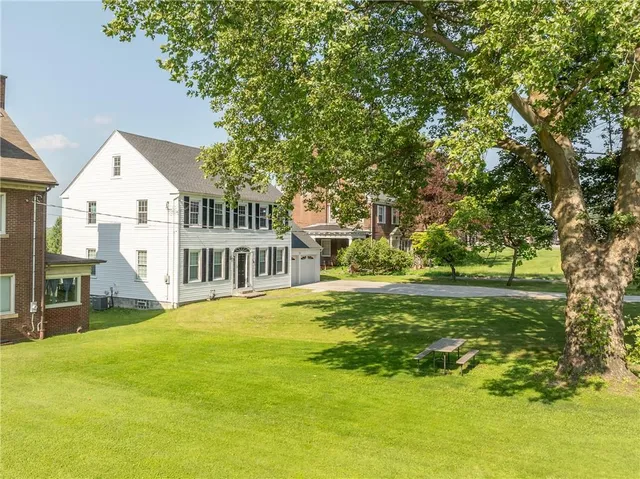 a view of a house with a big yard and large trees