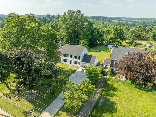 an aerial view of a house with garden space and trees all around