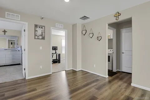 a view of a hallway with wooden floor and a bathroom