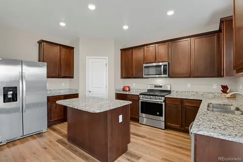 a kitchen with stainless steel appliances granite countertop a stove a sink dishwasher a refrigerator and a microwave oven with wooden floor