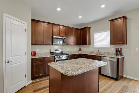 a kitchen with kitchen island granite countertop stainless steel appliances stove microwave refrigerator and sink
