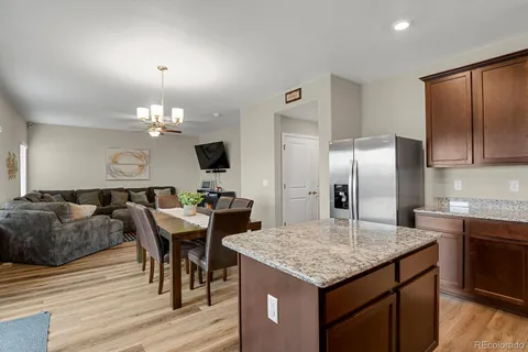 a kitchen with granite countertop kitchen island stainless steel appliances a sink stove and refrigerator with wooden floor
